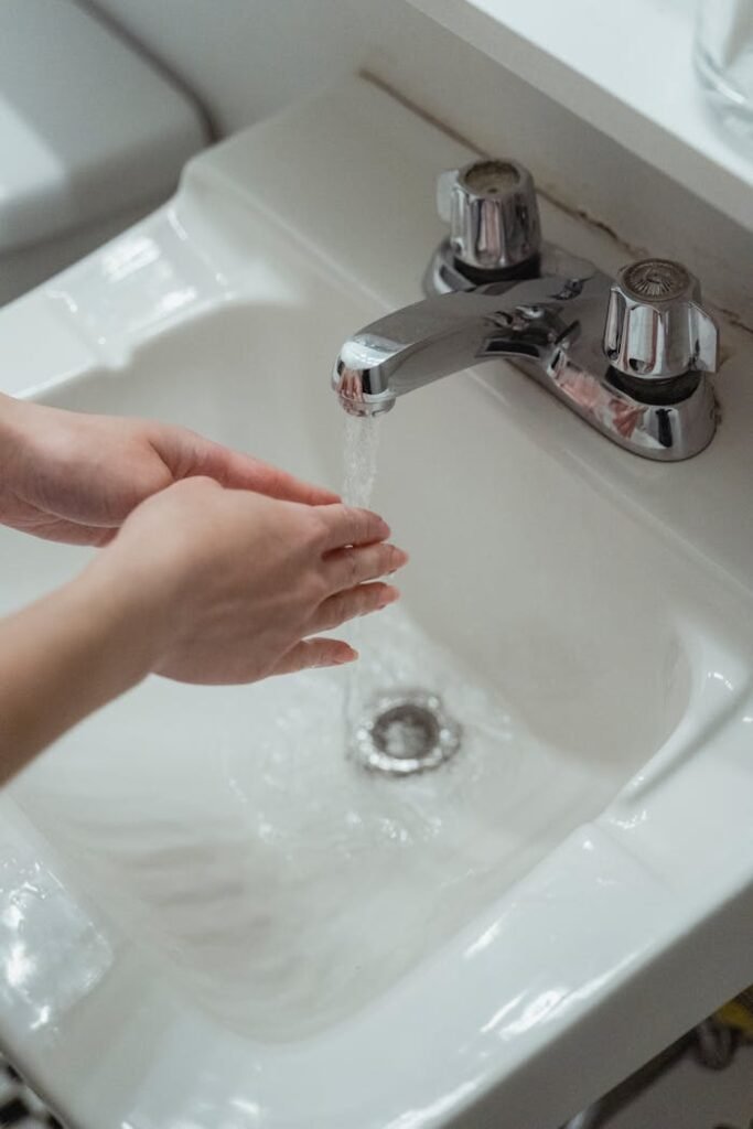 Person Washing Hands on Washbasin 